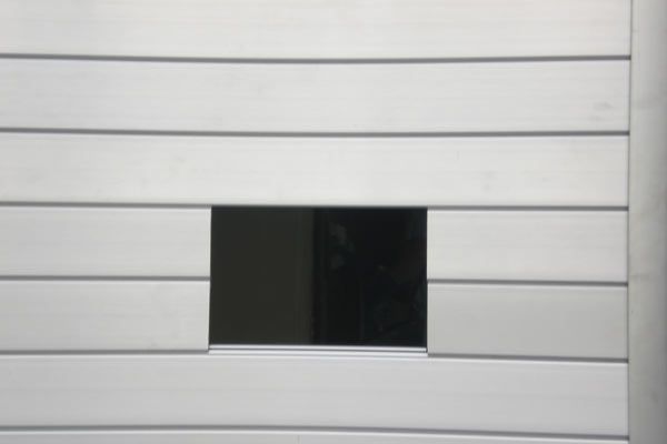 Una pared blanca con una pequeña ventana en el medio.