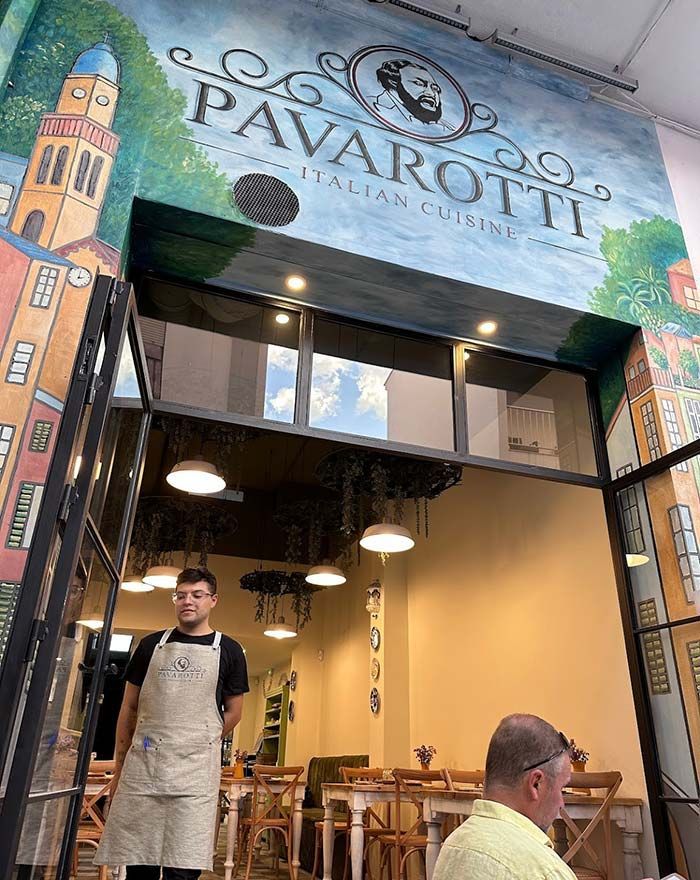 Un hombre con delantal está parado frente a un restaurante.