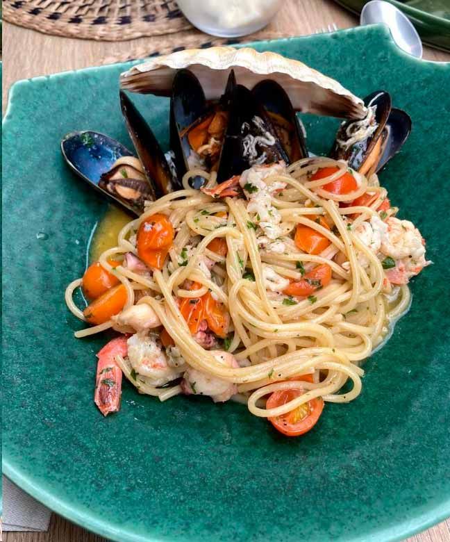 Un plato verde cubierto con espaguetis, mejillones y camarones.