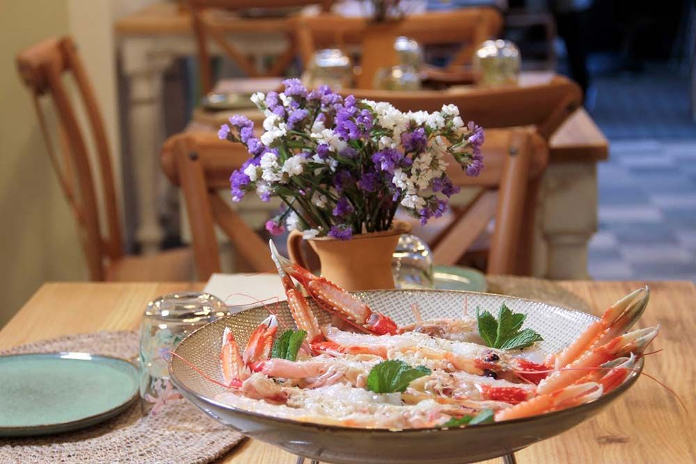 Un plato de camarones está sobre una mesa de madera al lado de un jarrón de flores.