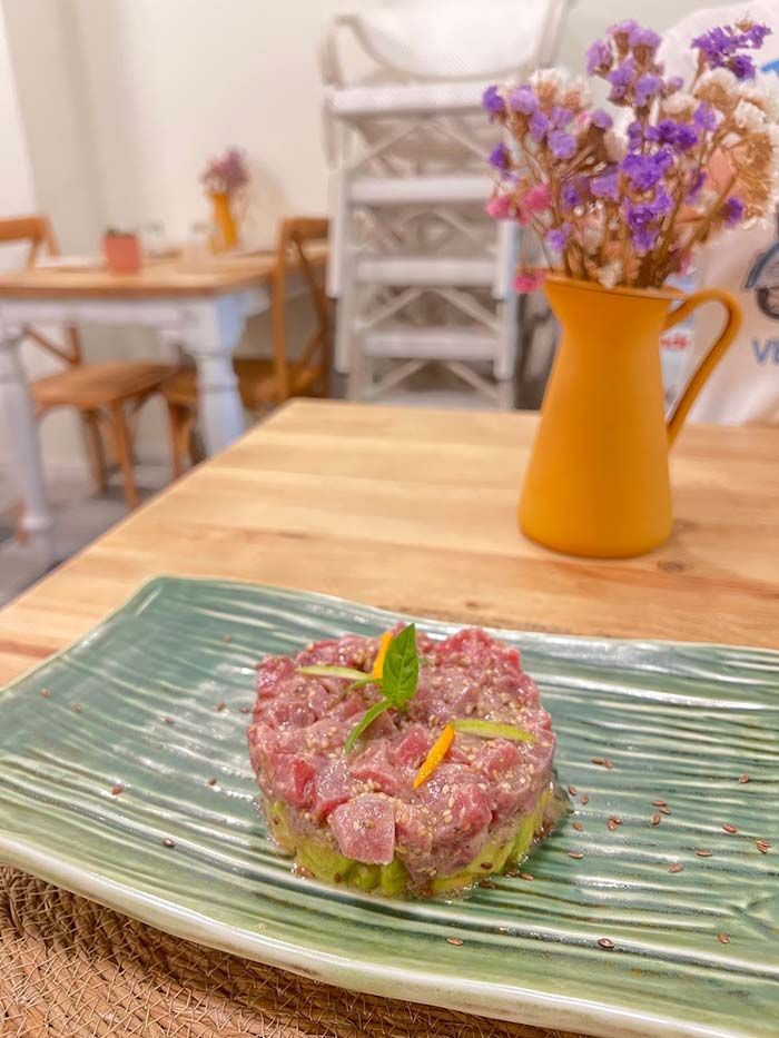 Un plato de comida está sobre una mesa de madera al lado de un jarrón con flores.