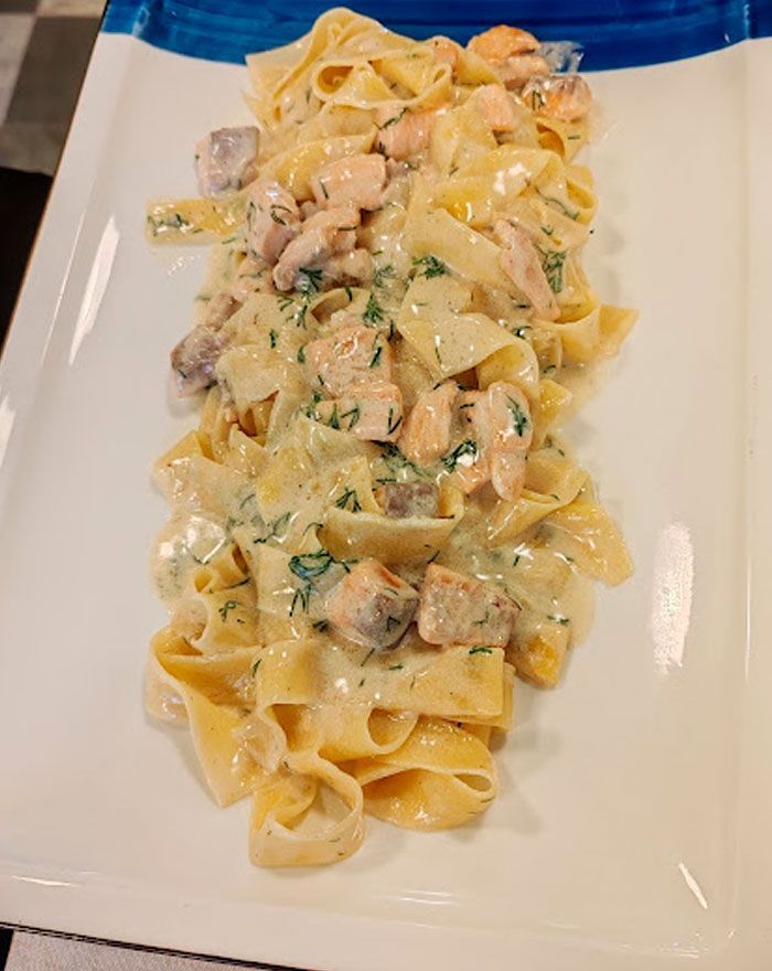 Un plato blanco cubierto con pasta y salsa sobre una mesa.