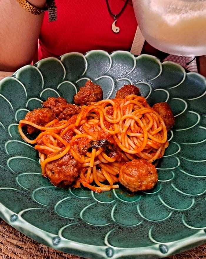 Un plato verde con espaguetis y albóndigas encima.