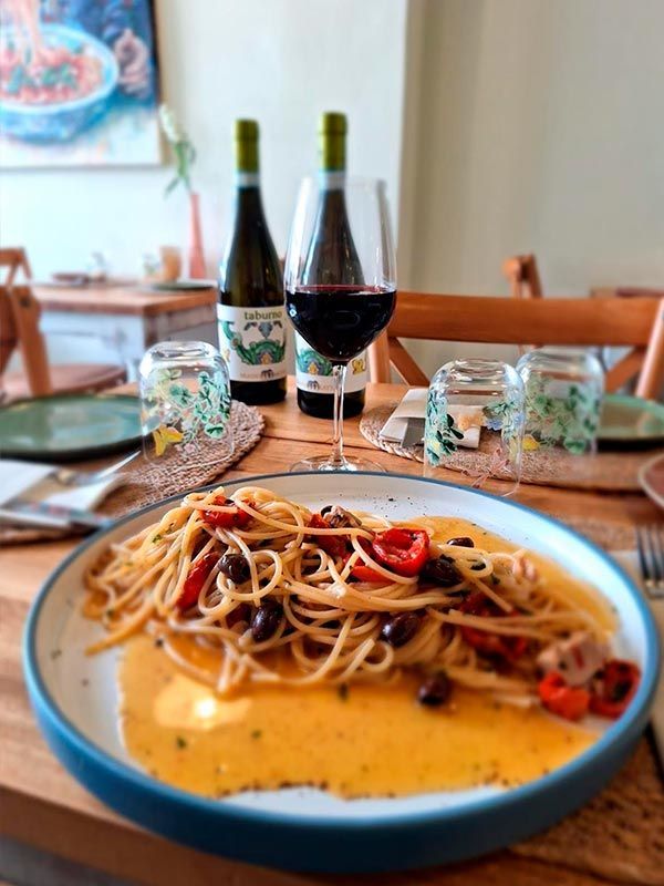 Un plato de espaguetis y una copa de vino en una mesa.