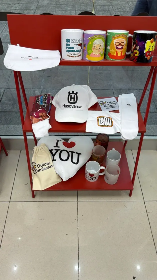 Estante rojo con tazas, gorras, camisetas, botellas y otros artículos personalizados impresos.