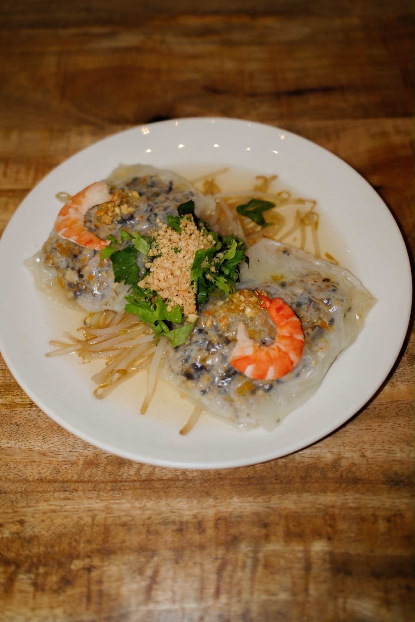 Assiette de pâtes aux crevettes à la sauce crémeuse, garnie d'herbes, sur une table en bois