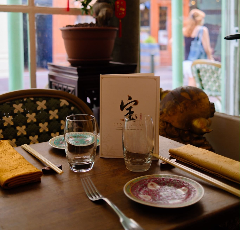 Table de restaurant dressée avec verres d'eau, couverts, pain et menu près d'une fenêtre