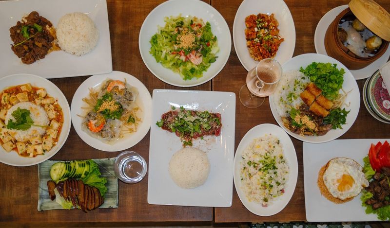 Assortiment de plats et de bols de riz disposés sur une table pour un repas à partager