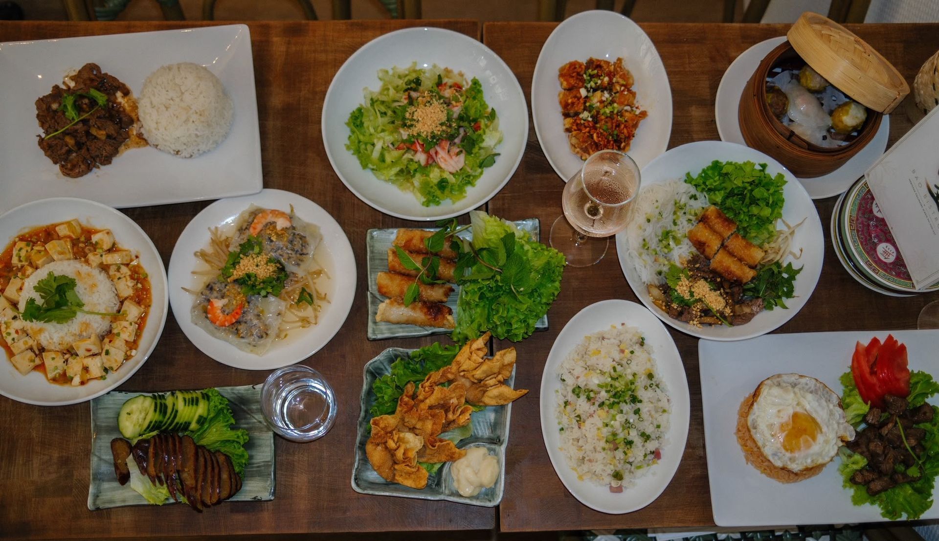 Assortiment de plats japonais présentés sur une table en bois, comprenant sushis, salades, tempuras et grillades.