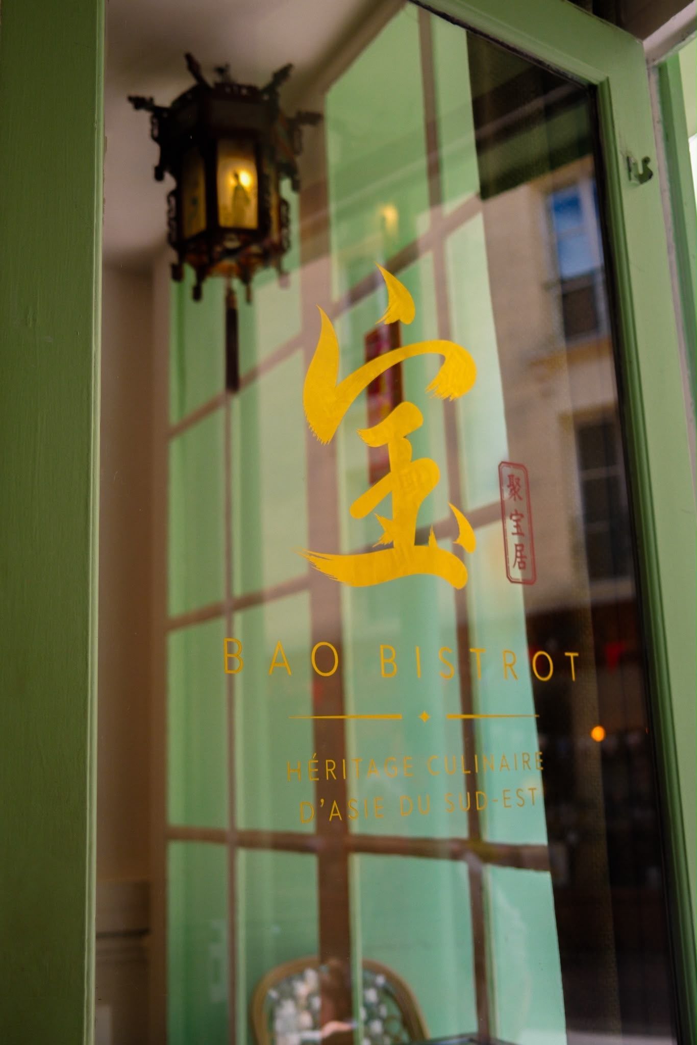 Porte vitrée de façade avec inscriptions chinoises dorées et lanterne suspendue à gauche