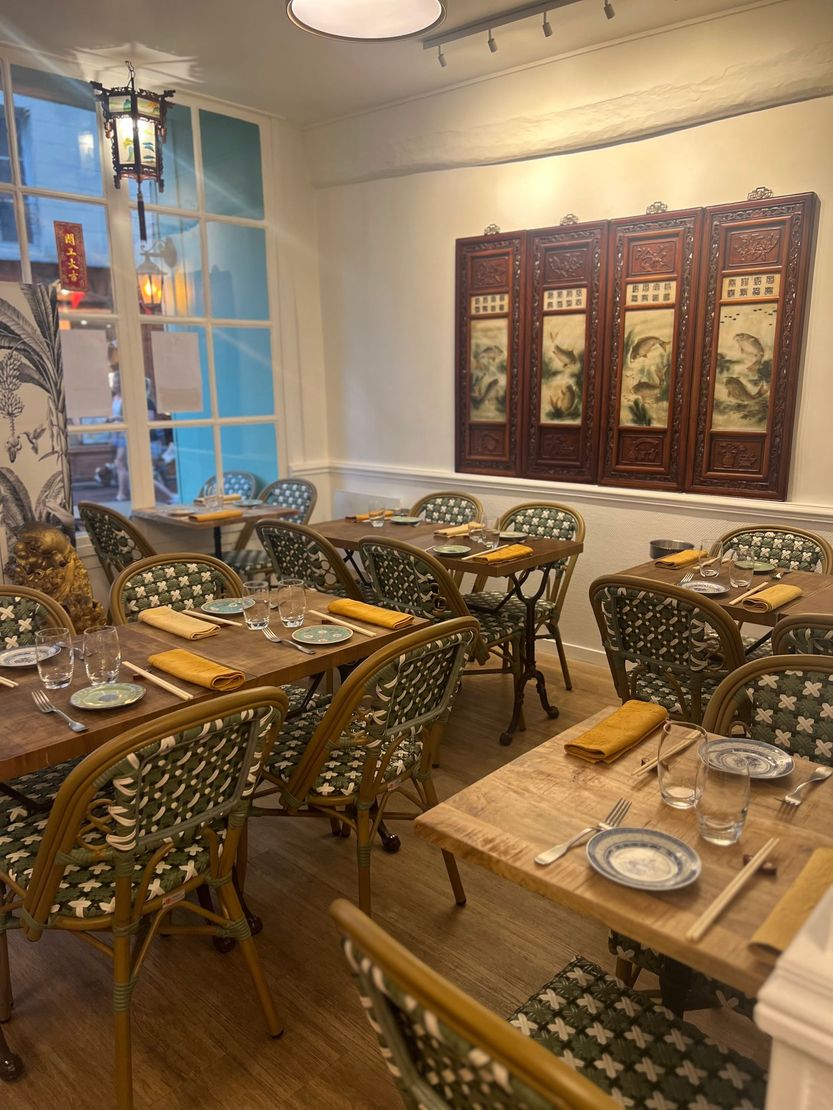 Salle à manger de restaurant confortable avec tables en bois, chaises à motifs et panneaux muraux sculptés
