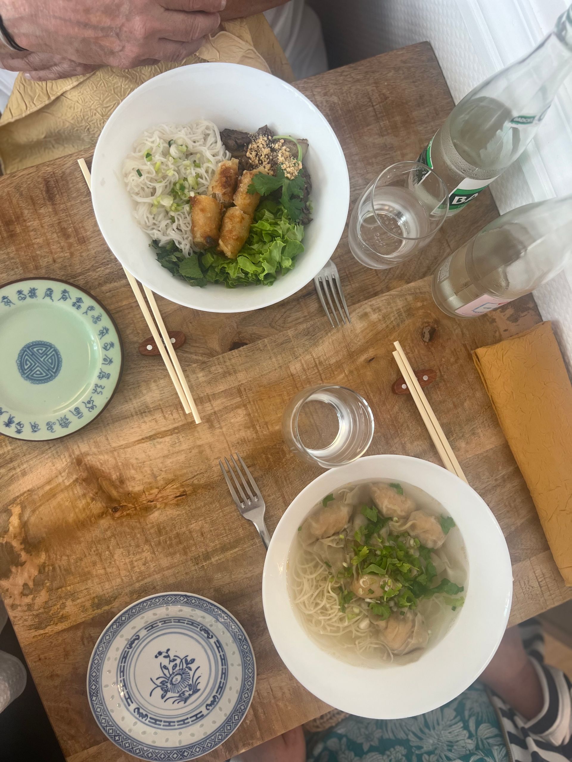 Vue de dessus d'une table de repas avec deux bols de nouilles, des baguettes, des verres et des assiettes à motifs.