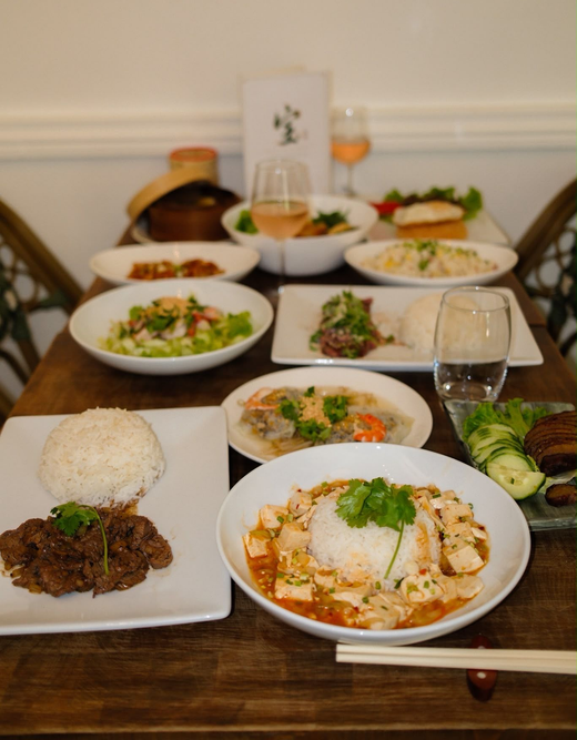 Table dressée avec plusieurs plats et verres d'eau pour un repas à l'intérieur.