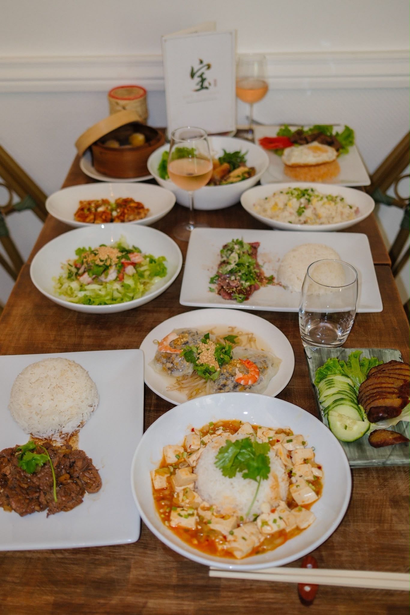 Table dressée sur une table en bois avec un assortiment de plats, riz, curry, salade et boissons.