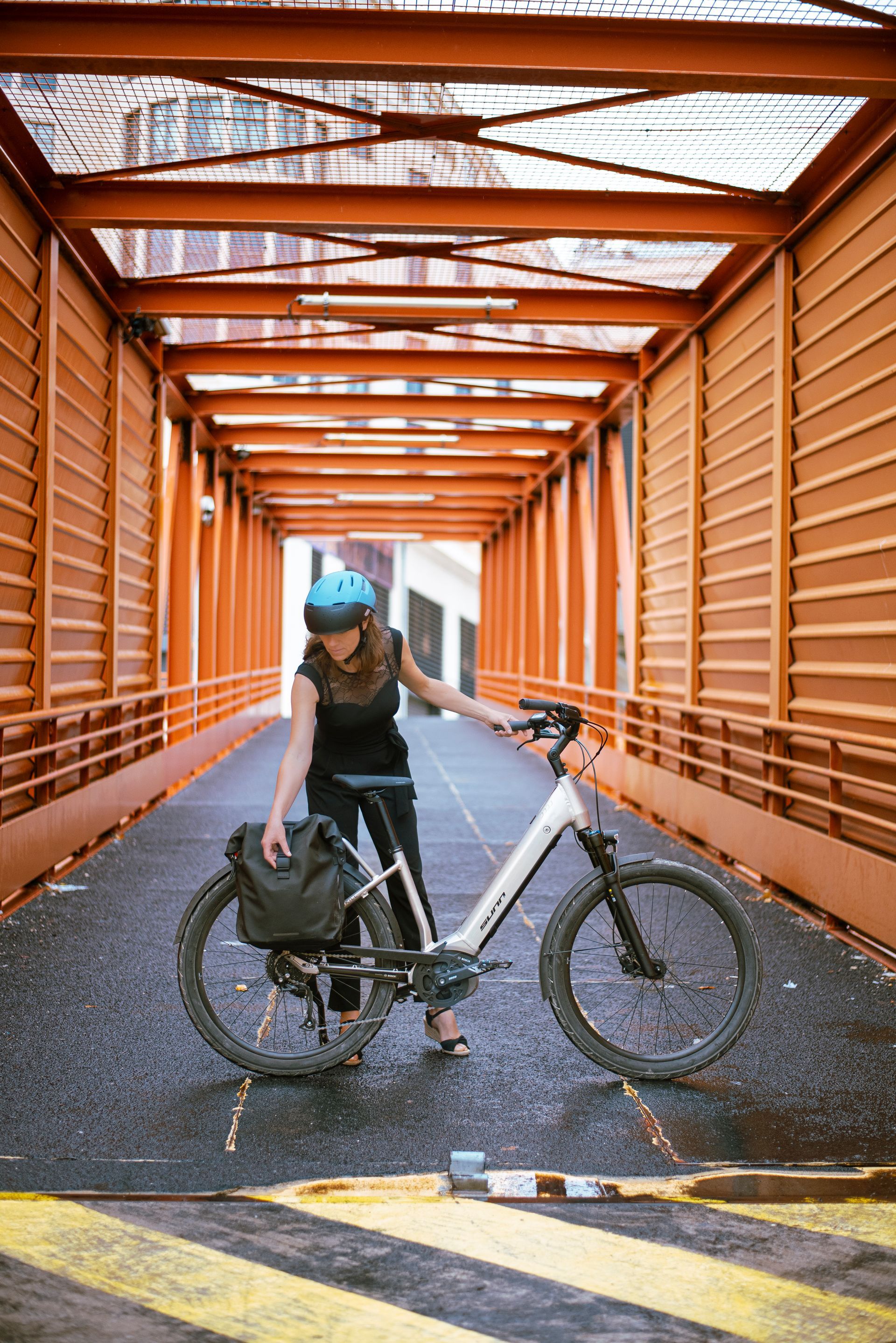 Une femme avec son vélo électrique, dans un tunnel sur un pont