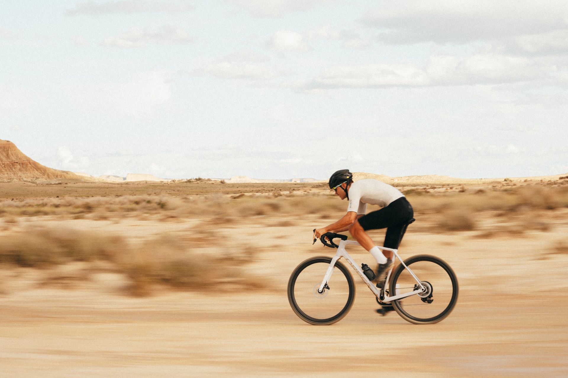 Un homme dans un milieu aride roule sur un vélo gravel
