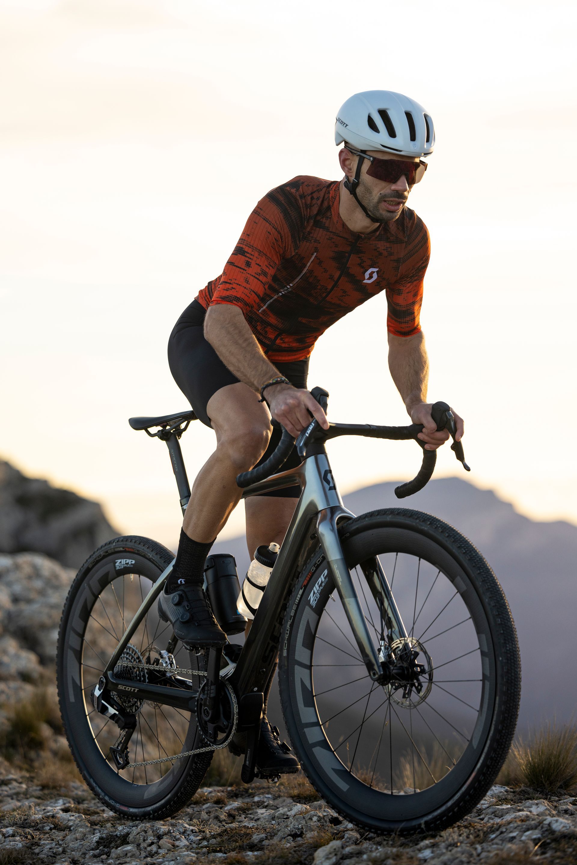 Un homme avec un t-shirt rouge roule sur un gravel bike