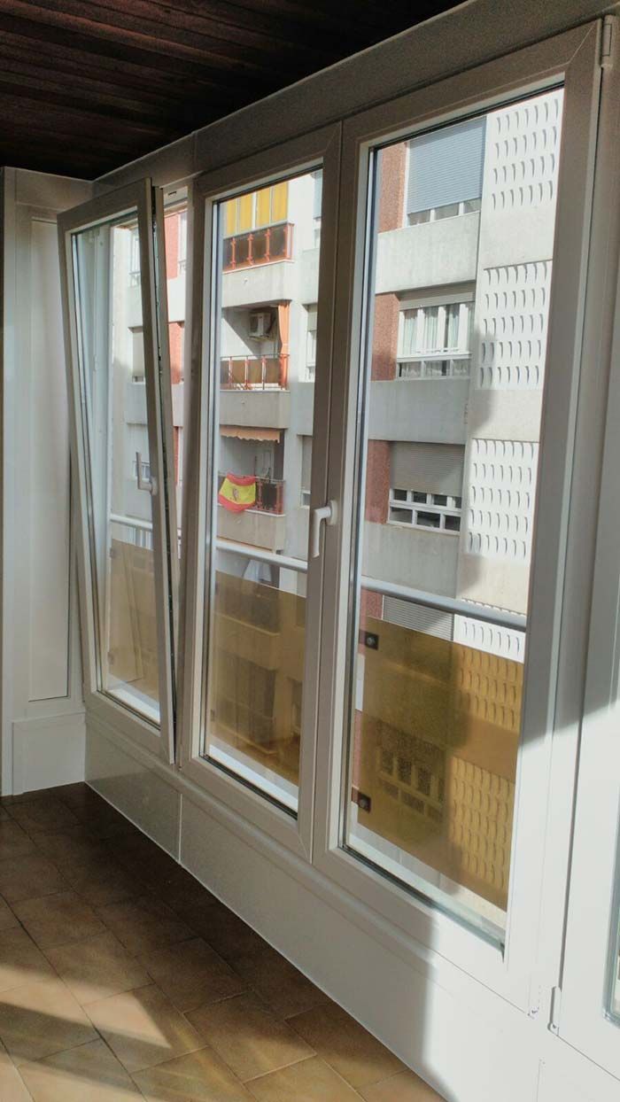 Una habitación con muchas ventanas y balcón.