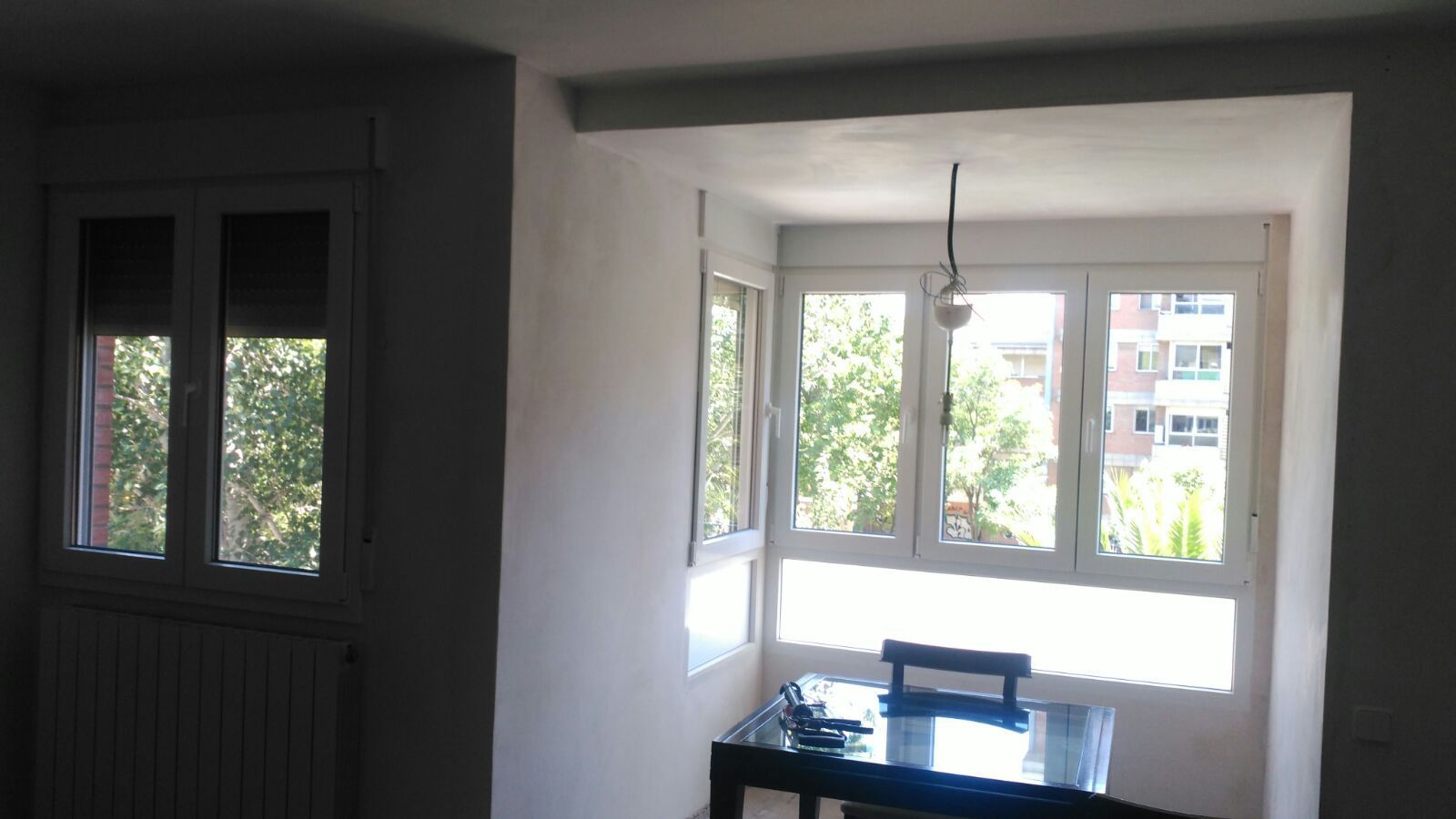 Una habitación con una mesa y sillas frente a una ventana.