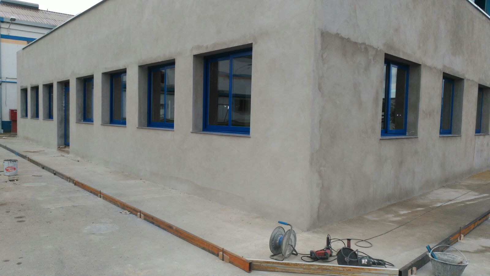 Se está construyendo un edificio de hormigón con ventanas azules.