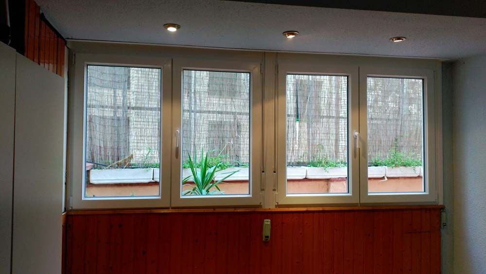 Una habitación con tres ventanas y una pared de madera.