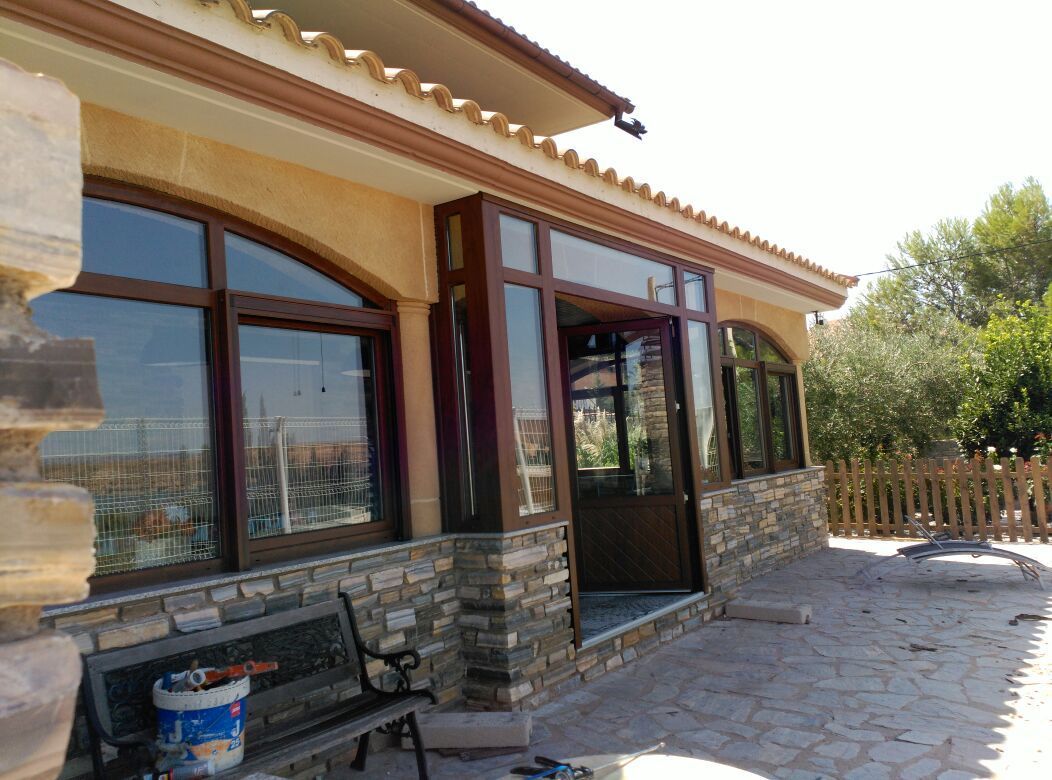 Una casa con muchas ventanas y un banco delante de ella.