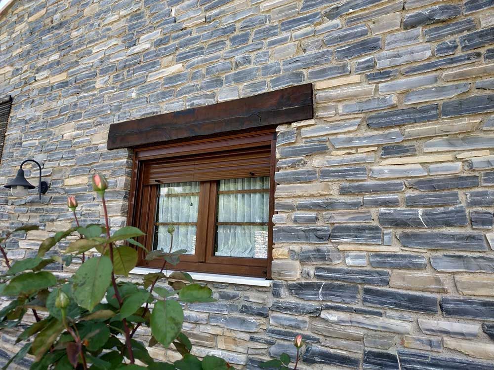 Un muro de piedra con una ventana y una planta delante.
