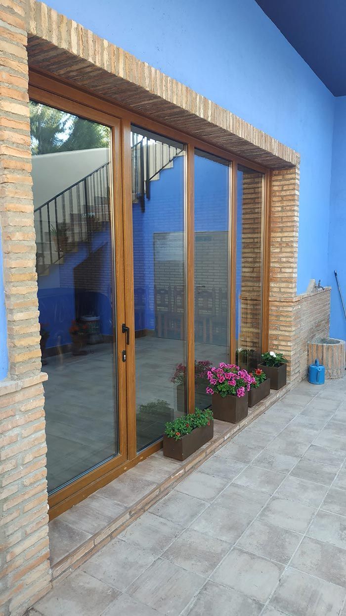Un patio con puertas corredizas de vidrio y jardineras con flores.