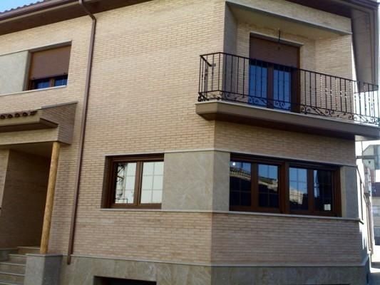 Una casa con balcón y muchas ventanas