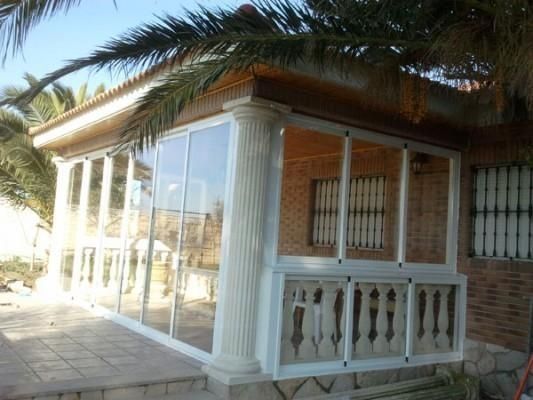 Una casa con un porche y una palmera al fondo.