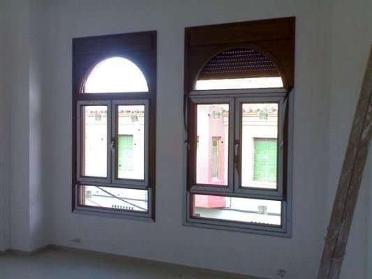 Una habitación vacía con dos ventanas y una escalera.