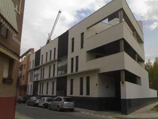 Un edificio con coches aparcados delante.