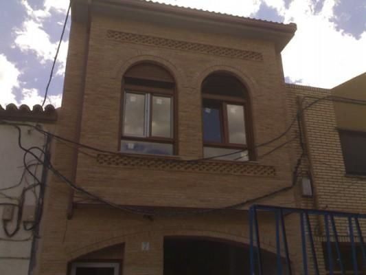 Un edificio de ladrillo con ventanas arqueadas y una barandilla azul.
