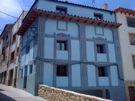 Un edificio azul con un muro de piedra delante.