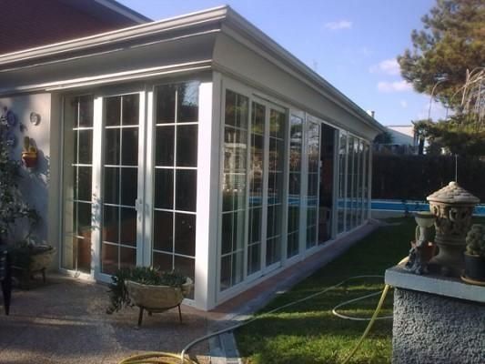 Una casa con muchas ventanas y una piscina al fondo.