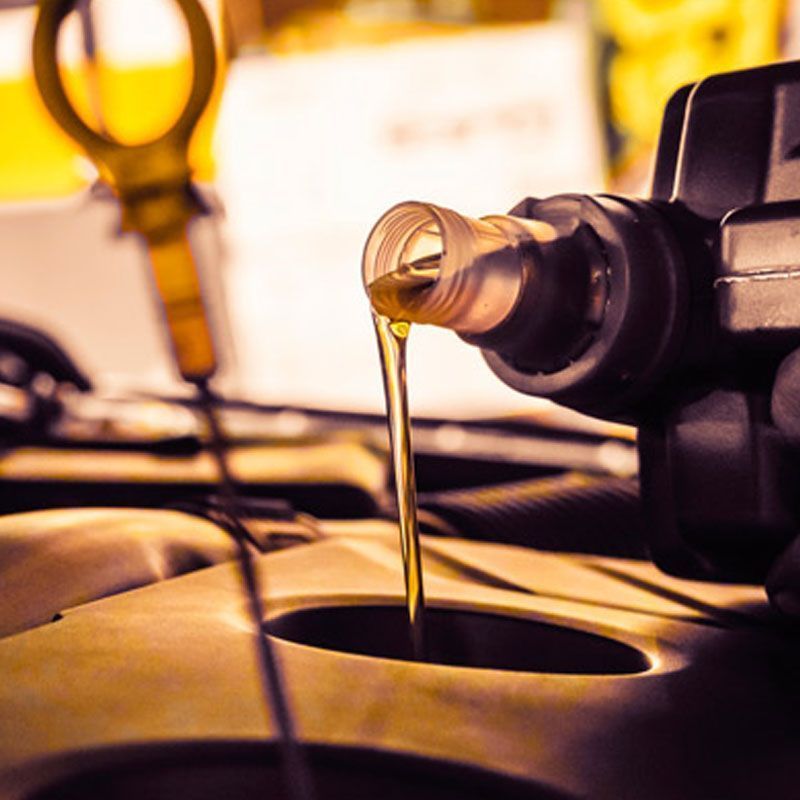 Aceite de motor vertiéndose de una botella en la abertura de llenado del motor.