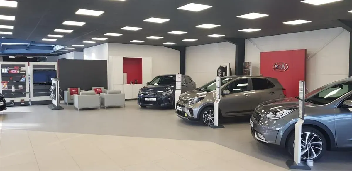 Heller Autohausraum mit mehreren geparkten Fahrzeugen unter Deckenleuchten