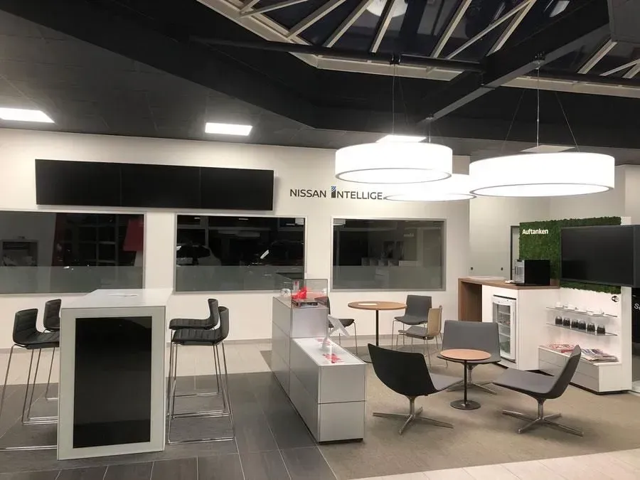 Moderne Bürolounge mit weißen Theken, schwarzen Stühlen und runden Hängeleuchten