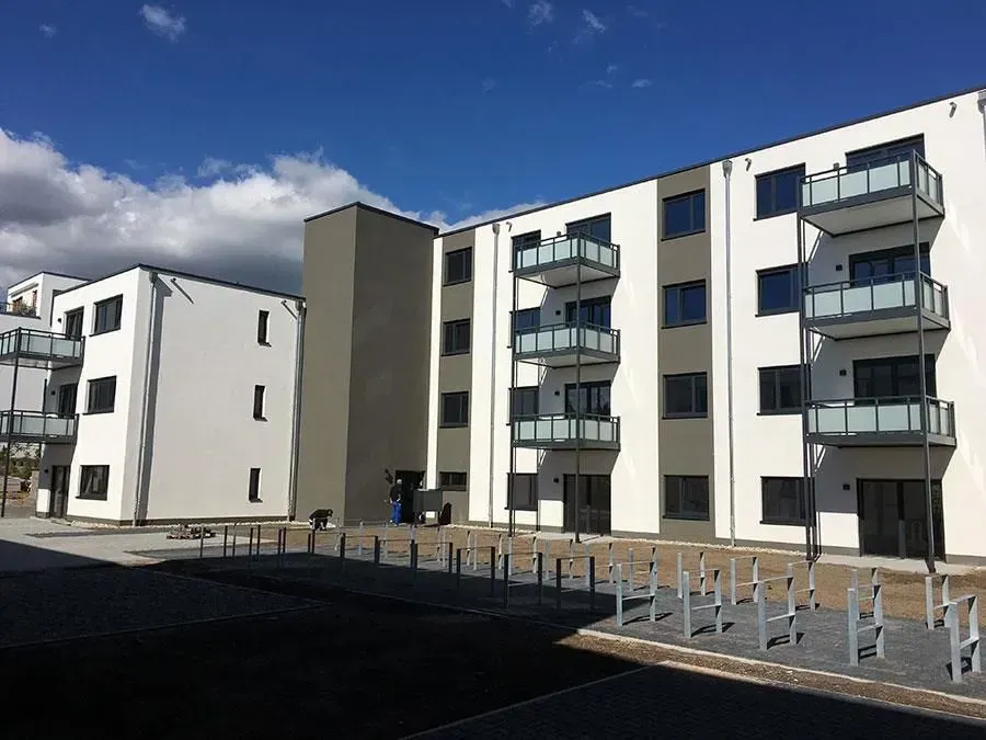 Moderne Wohngebäude mit Balkonen und Fahrradständern unter blauem Himmel.