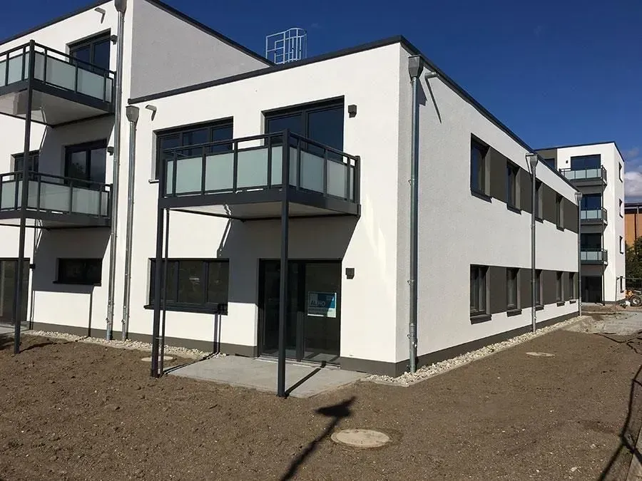 Moderne weiße Wohnhäuser mit dunklen Balkonen in einem Kieshof