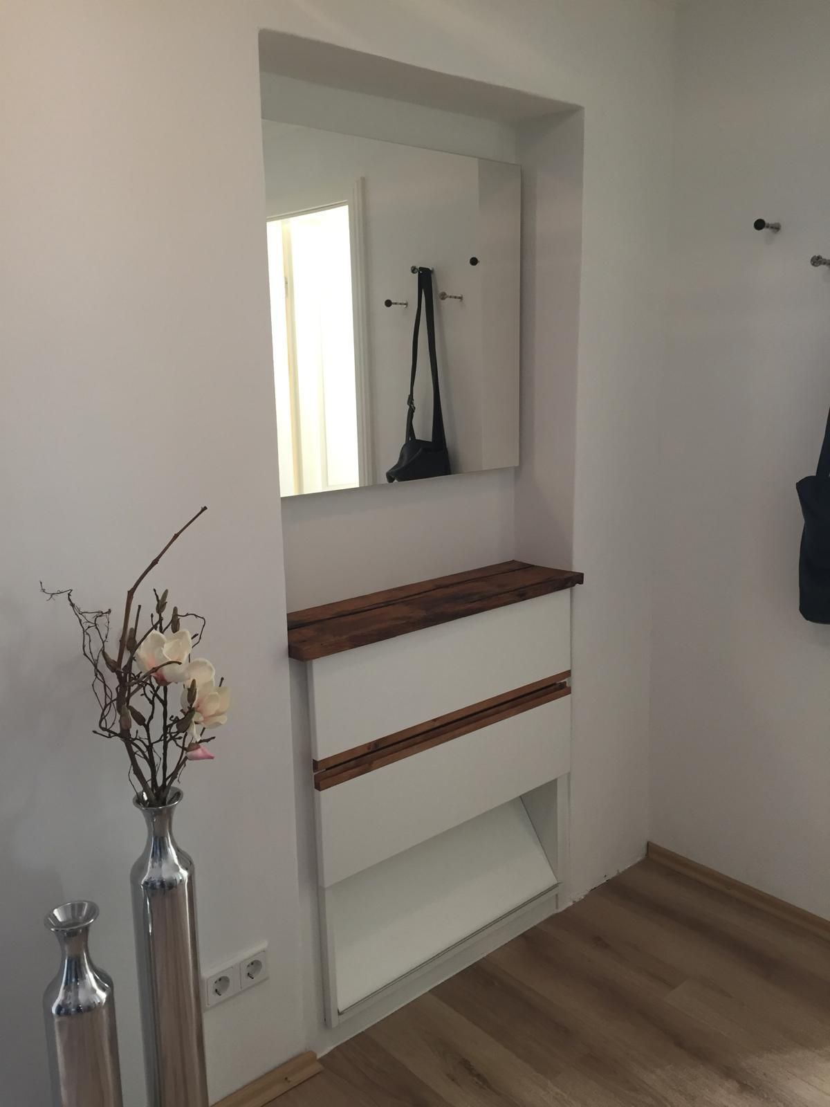 Ein Flur mit einer Blumenvase und einem Spiegel an der Wand.