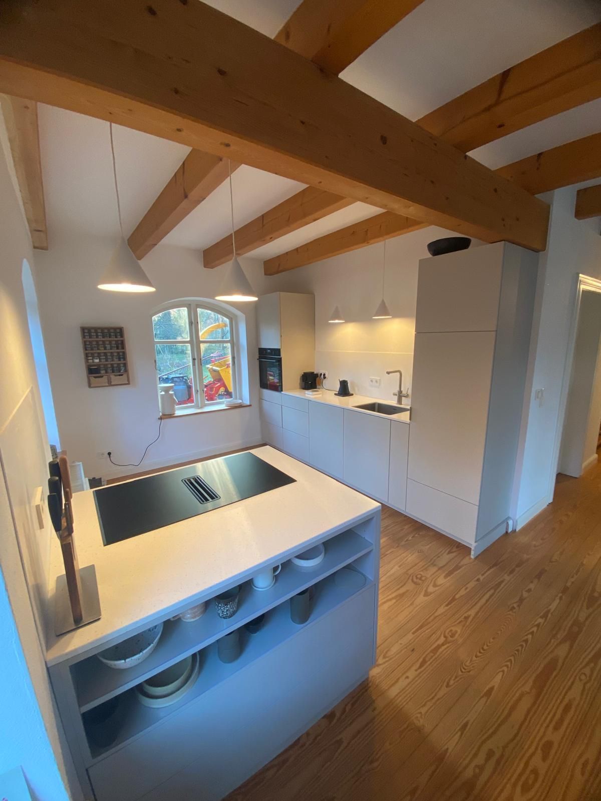 Eine Küche mit weißen Schränken und Holzbalken