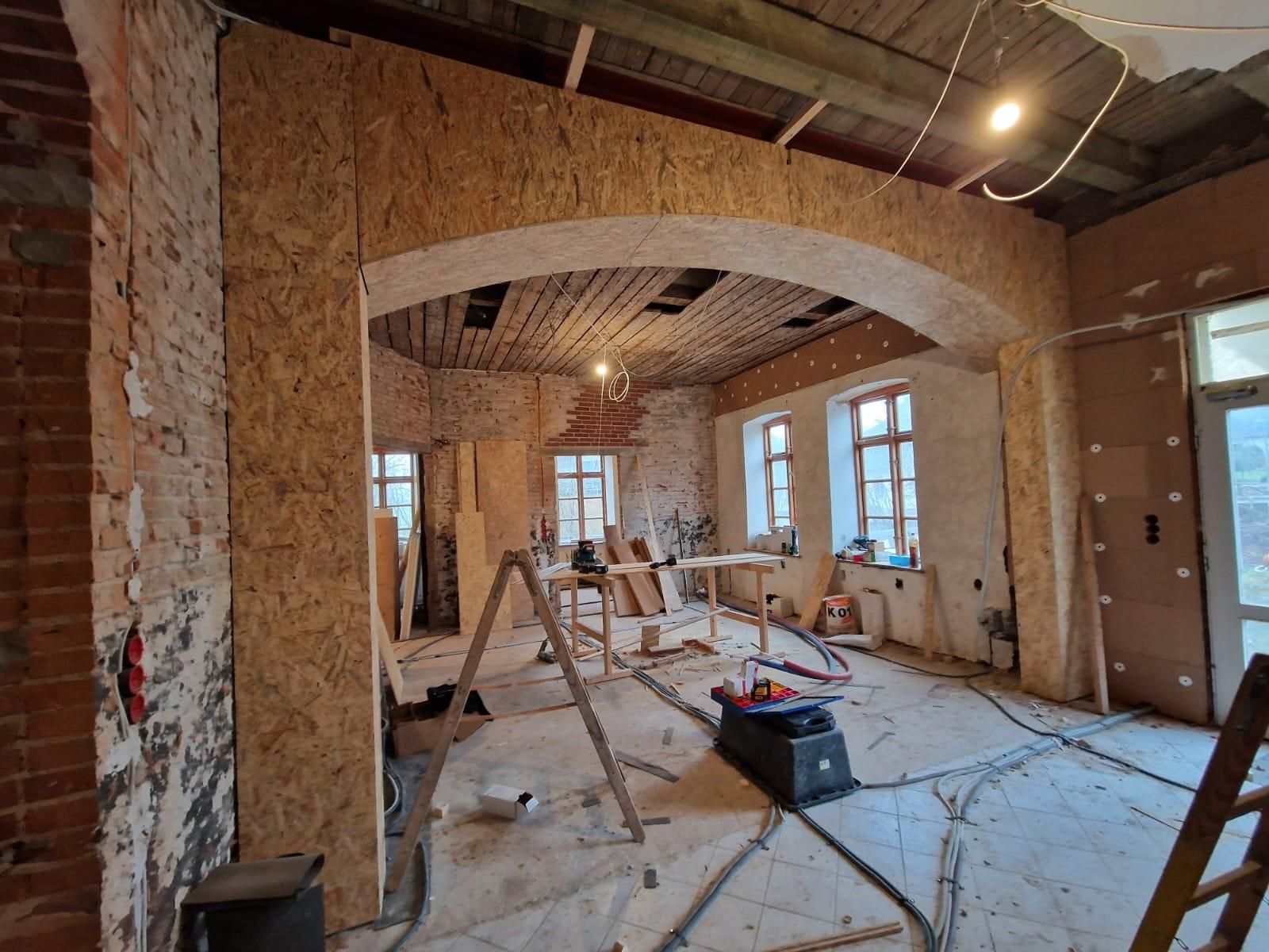 Ein großer Raum mit einer Leiter in der Mitte wird umgebaut.
