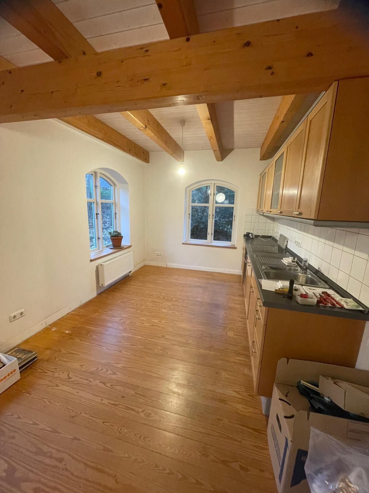 Eine leere Küche mit Holzschränken und Holzboden.