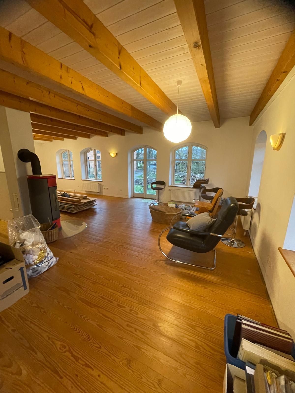 Ein Wohnzimmer mit Holzboden, einer Couch, einem Sessel und einem Kamin.