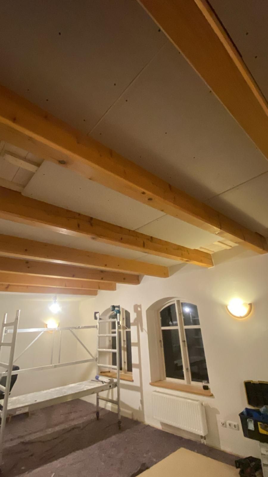 Ein Raum mit Holzbalken und einer Leiter darin.