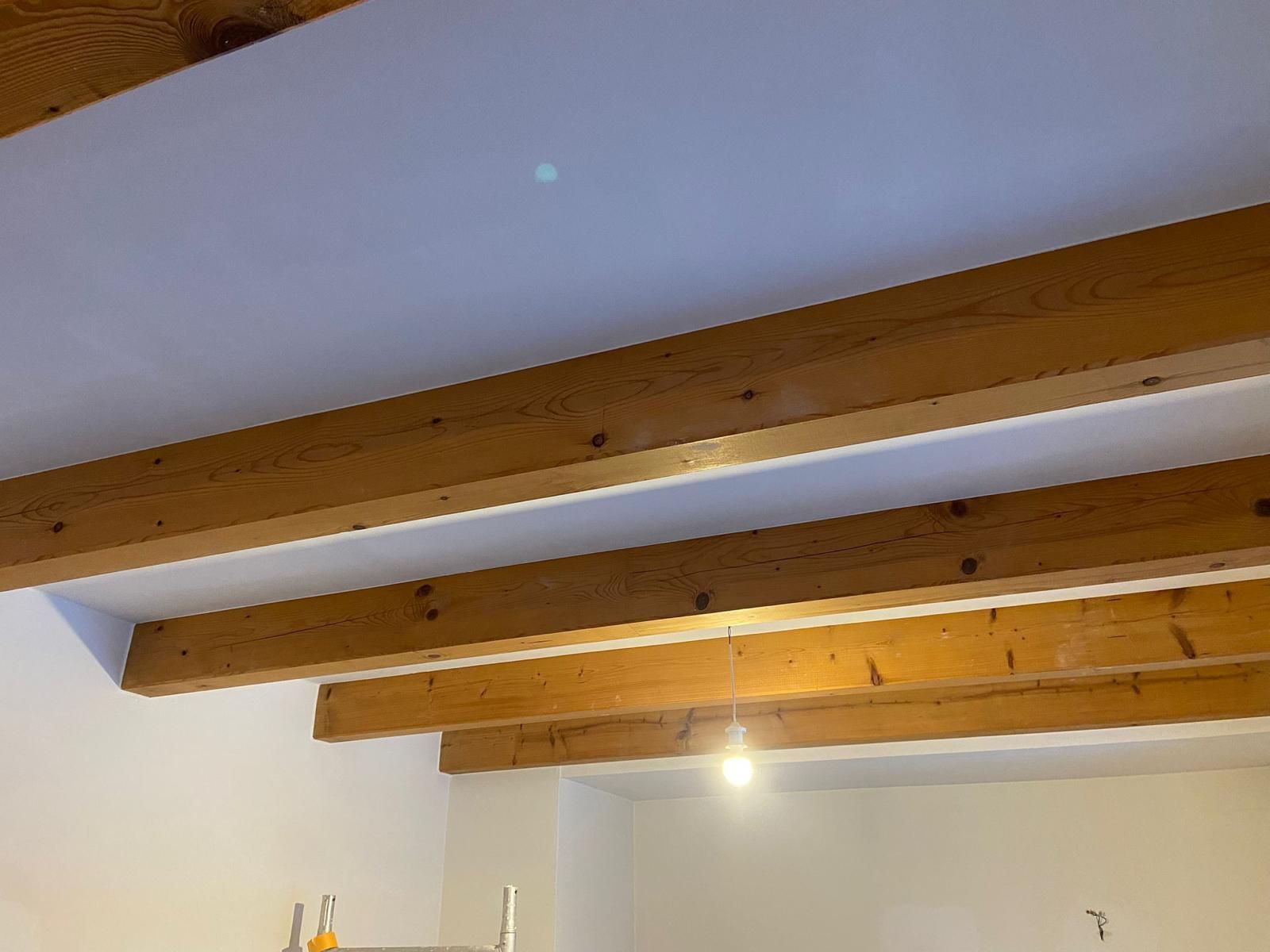 Eine Decke mit Holzbalken und einer daran hängenden Lampe