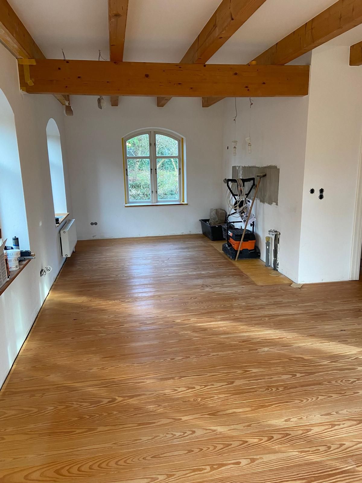 Ein großer Raum mit Holzboden und weißen Wänden.