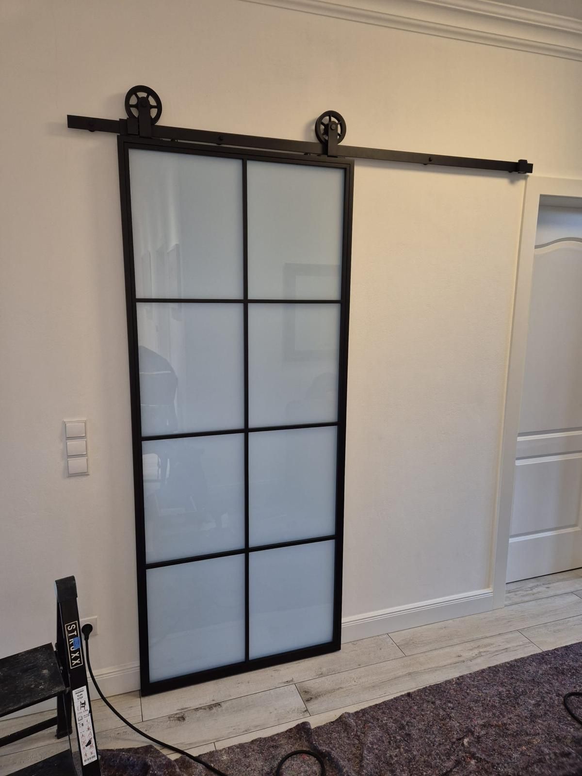 In einem Wohnzimmer wird eine Glasschiebetür eingebaut.