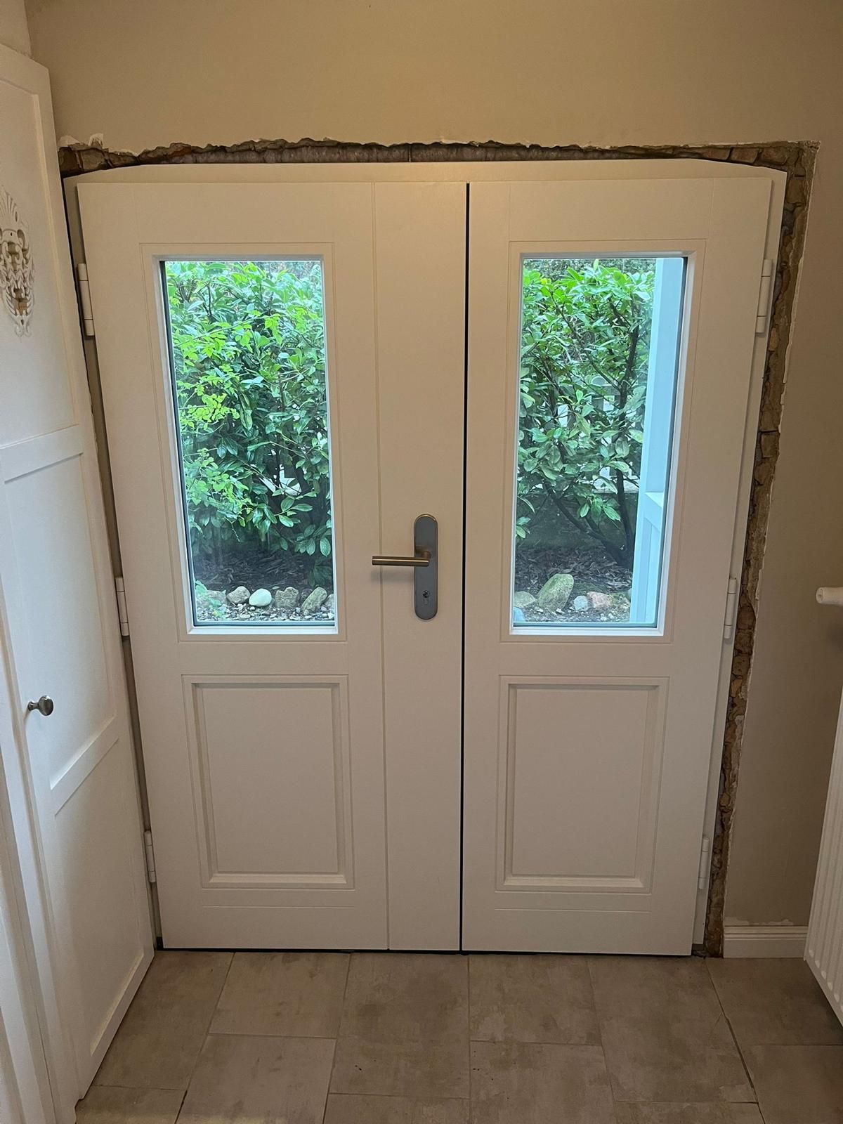 Ein Paar weiße Doppeltüren mit zwei Fenstern in einem Raum.